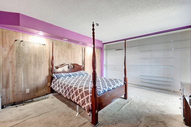 bedroom featuring a textured ceiling, wood walls, and carpet