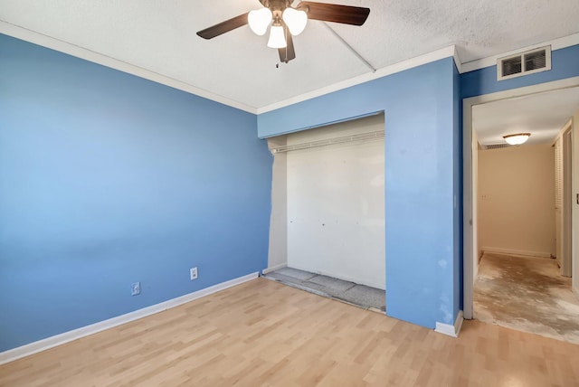 unfurnished bedroom featuring visible vents, ornamental molding, wood finished floors, a textured ceiling, and a closet