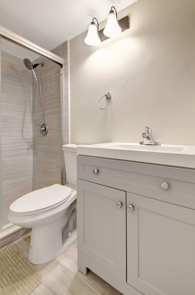 full bathroom featuring toilet, a shower stall, and vanity