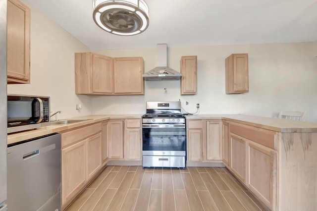 kitchen featuring light brown cabinetry, appliances with stainless steel finishes, wall chimney exhaust hood, and wood tiled floor