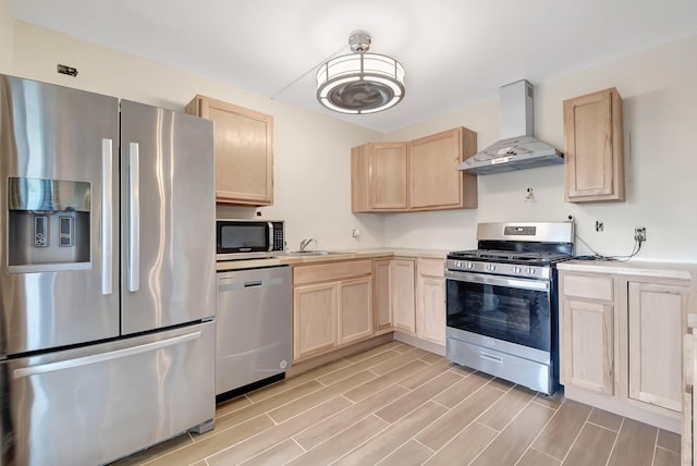 kitchen with wood finish floors, light countertops, appliances with stainless steel finishes, light brown cabinets, and wall chimney exhaust hood