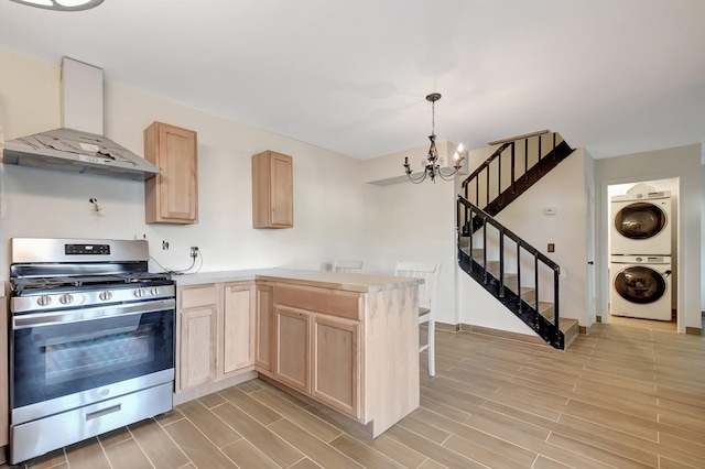 kitchen with stacked washer and clothes dryer, stainless steel range with gas cooktop, wood tiled floor, light brown cabinets, and exhaust hood