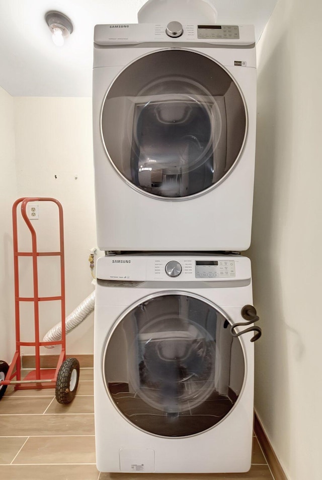 laundry room featuring laundry area, stacked washing maching and dryer, and baseboards