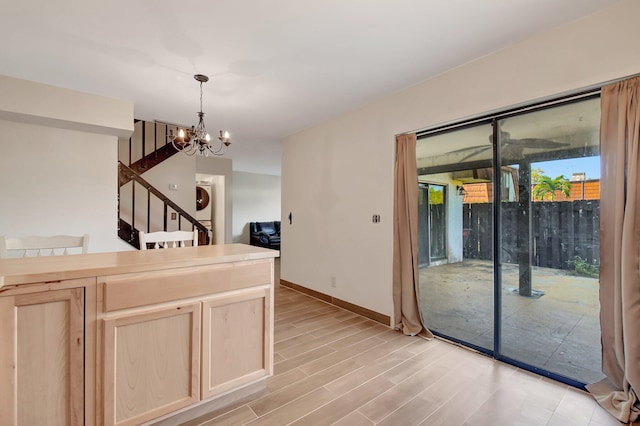 kitchen featuring light brown cabinetry, light wood-style floors, stacked washer and dryer, and a notable chandelier