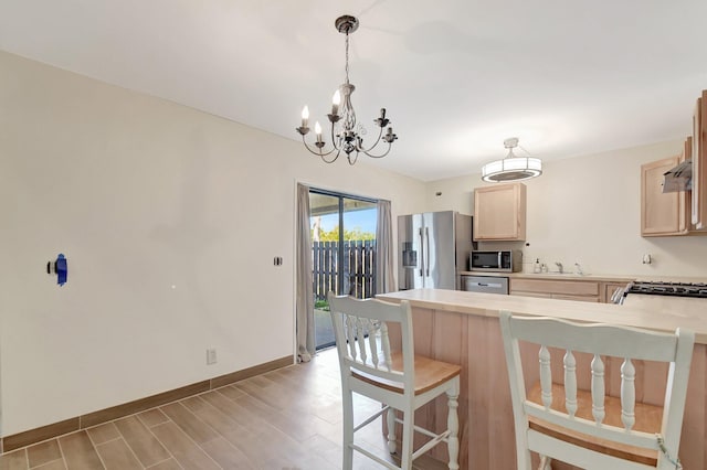 kitchen featuring a peninsula, stainless steel appliances, light countertops, and light brown cabinetry