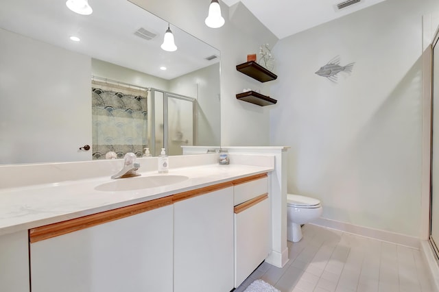 bathroom featuring toilet, vanity, visible vents, baseboards, and a stall shower