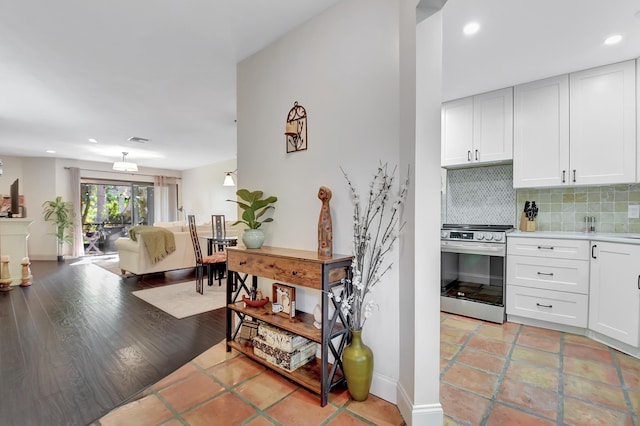 kitchen with tasteful backsplash, recessed lighting, white cabinetry, and stainless steel electric range