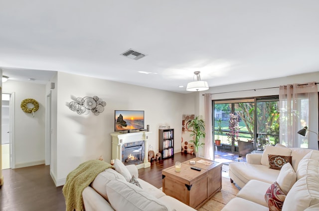 living area with light wood-type flooring, baseboards, visible vents, and a glass covered fireplace