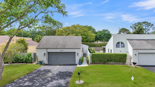 view of front facade with driveway, fence, a front lawn, and stucco siding