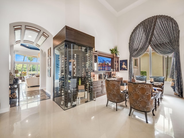 interior space with arched walkways, baseboards, a towering ceiling, and crown molding