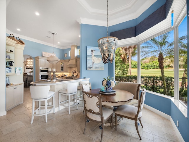 dining space with baseboards, a chandelier, stone tile flooring, and ornamental molding