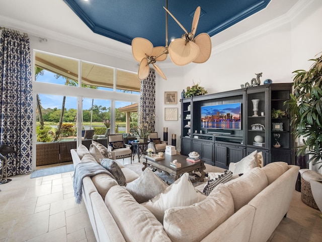 living area with stone tile flooring, a high ceiling, a tray ceiling, and crown molding