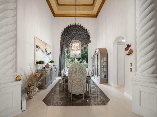 dining area with arched walkways, ornamental molding, a high ceiling, and an inviting chandelier