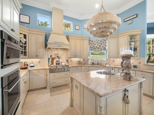 kitchen featuring crown molding, a center island with sink, and cream cabinets