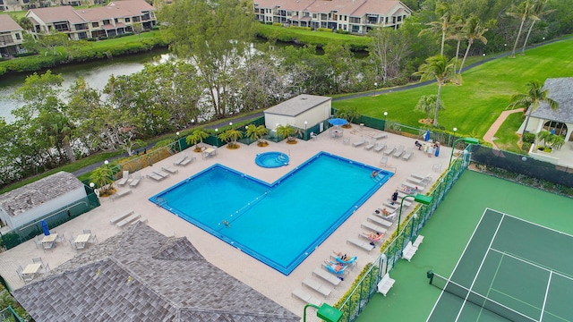 pool with a water view, a patio area, fence, and an outbuilding