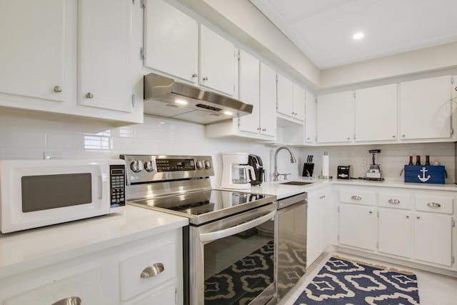 kitchen with stainless steel appliances, decorative backsplash, white cabinetry, a sink, and under cabinet range hood