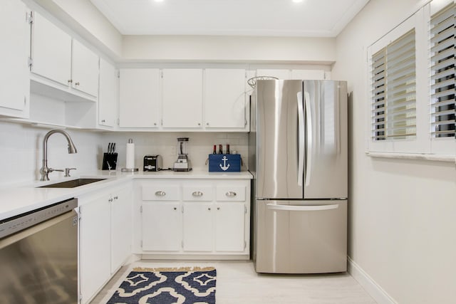 kitchen featuring appliances with stainless steel finishes, a sink, white cabinets, and decorative backsplash