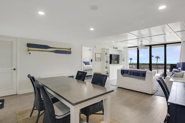 dining space featuring baseboards, a wall of windows, wood finished floors, and recessed lighting