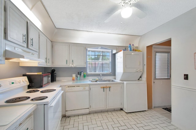 kitchen with white appliances, under cabinet range hood, light countertops, stacked washing maching and dryer, and a sink