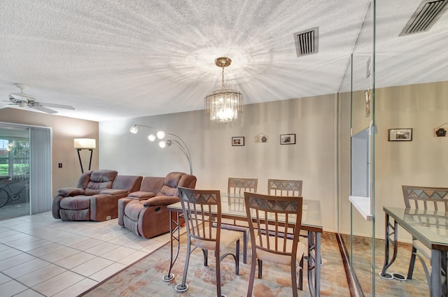 dining area with ceiling fan with notable chandelier, visible vents, a textured ceiling, and light tile patterned flooring