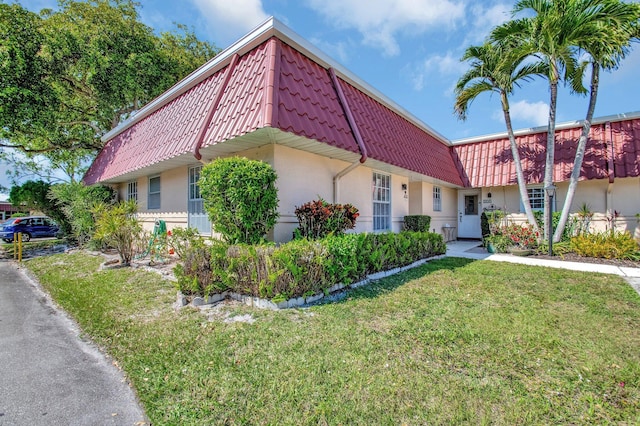 233 Down E Ln, Lake Worth, FL 33467 - townhome / multi-family property with mansard roof, stucco siding, and a front lawn