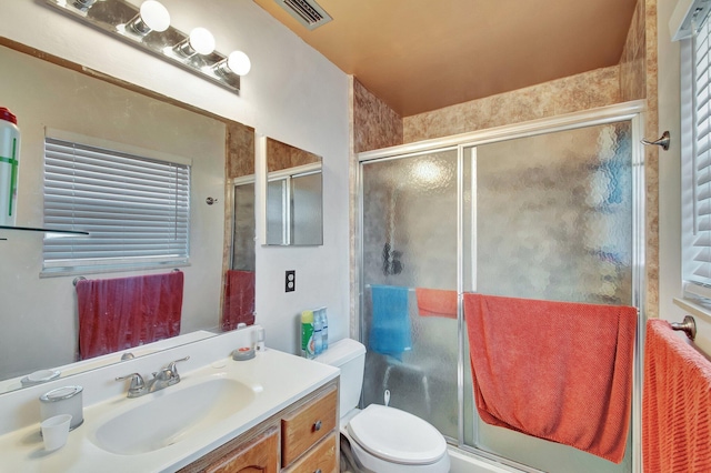 bathroom with toilet, a stall shower, vanity, and visible vents