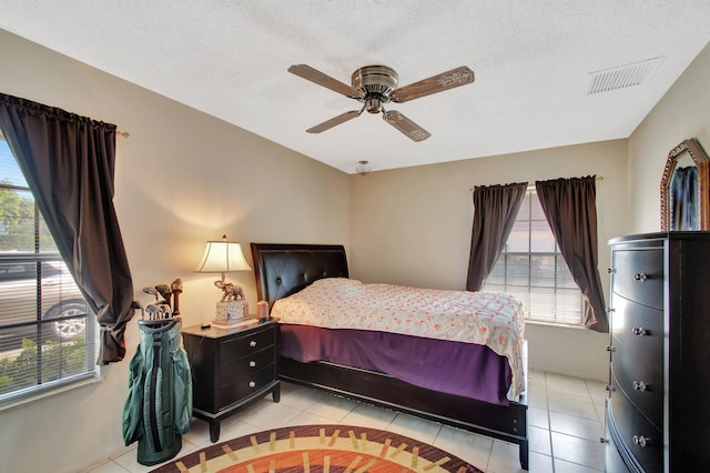 bedroom with a ceiling fan, visible vents, a textured ceiling, and light tile patterned floors