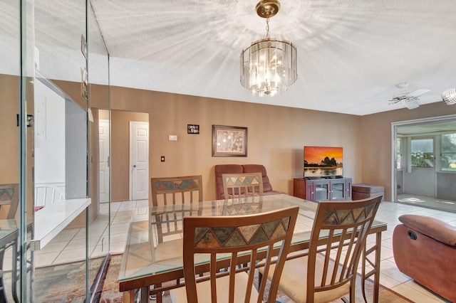 dining space with light tile patterned flooring, a textured ceiling, and ceiling fan with notable chandelier