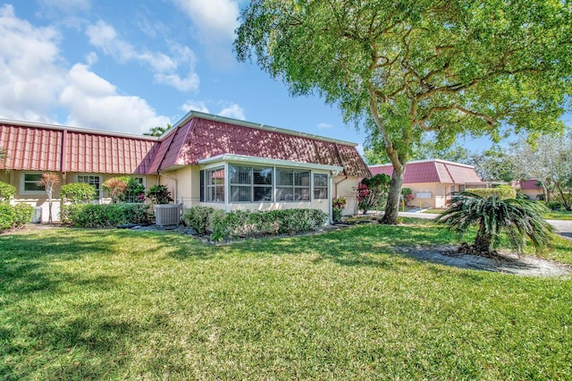 view of front of home with cooling unit, a tile roof, a front lawn, and mansard roof