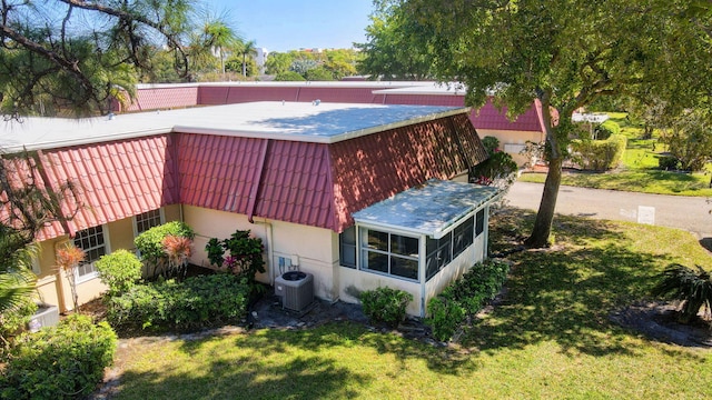 view of property exterior featuring cooling unit, a yard, a tiled roof, and stucco siding