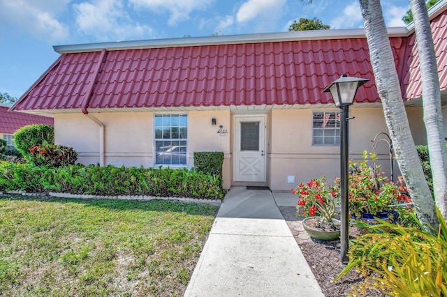 townhome / multi-family property featuring a tiled roof, a front lawn, and stucco siding