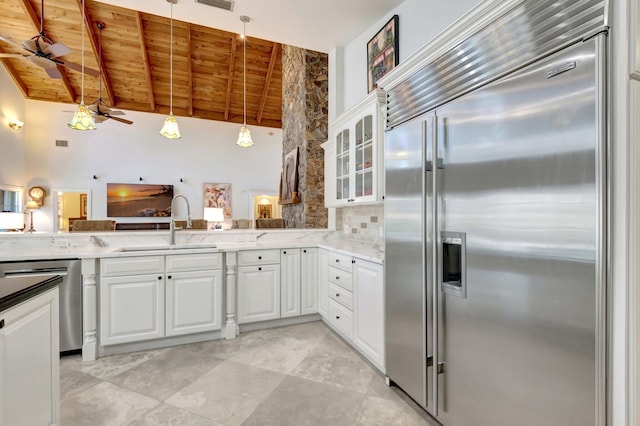 kitchen with vaulted ceiling with beams, wooden ceiling, stainless steel appliances, a ceiling fan, and glass insert cabinets