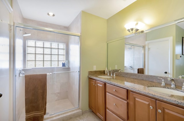 full bath with double vanity, a sink, and a shower stall