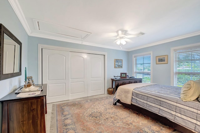 bedroom featuring a ceiling fan, attic access, ornamental molding, and a closet