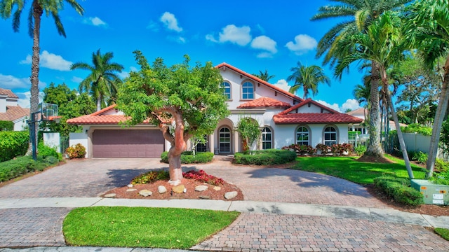 mediterranean / spanish home featuring decorative driveway, a tile roof, and fence