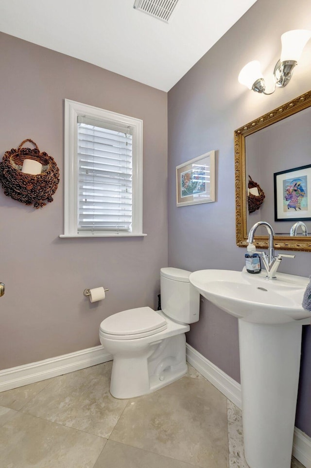 half bath featuring toilet, baseboards, and visible vents