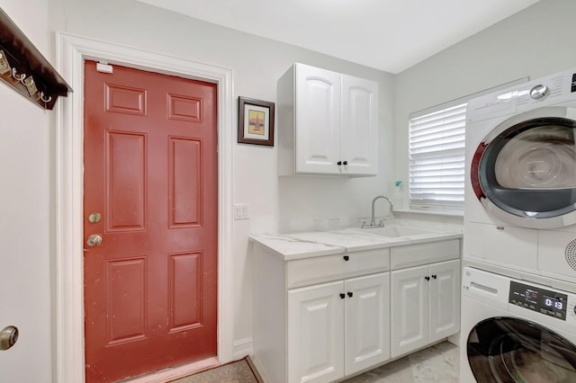 laundry room with stacked washer and dryer, cabinet space, and a sink