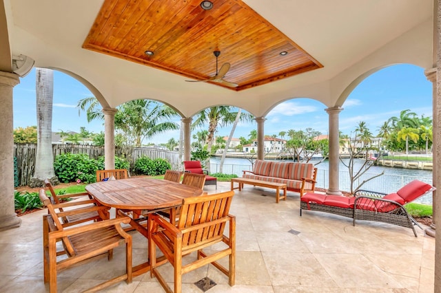 view of patio / terrace with a ceiling fan, outdoor dining area, a water view, and fence