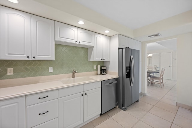 kitchen with visible vents, white cabinets, decorative backsplash, stainless steel appliances, and a sink