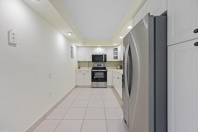 kitchen featuring light tile patterned floors, light countertops, appliances with stainless steel finishes, white cabinetry, and baseboards