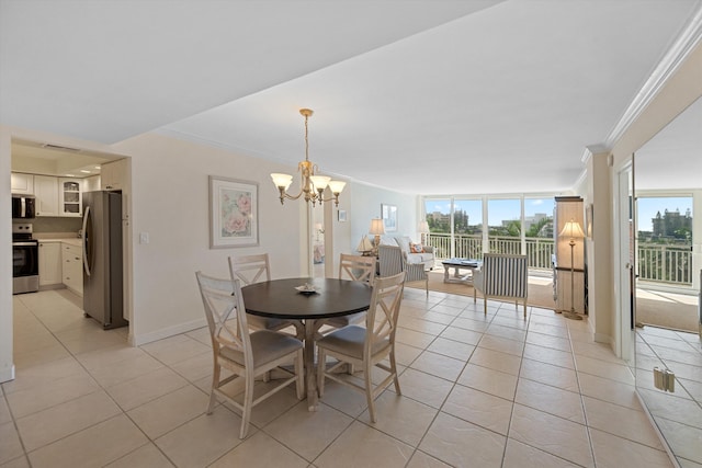 dining room featuring a notable chandelier, light tile patterned floors, ornamental molding, a wall of windows, and baseboards