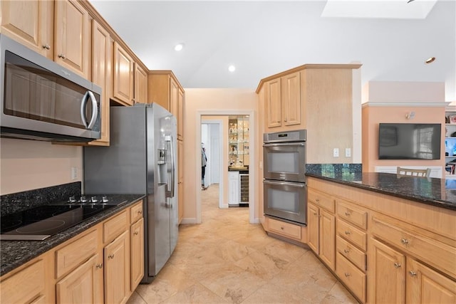 kitchen featuring dark stone counters, stainless steel appliances, light brown cabinetry, and recessed lighting