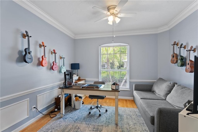 office area with crown molding, ceiling fan, wood finished floors, and wainscoting