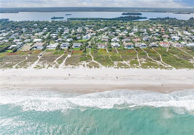 drone / aerial view with a water view, a view of the beach, and a residential view