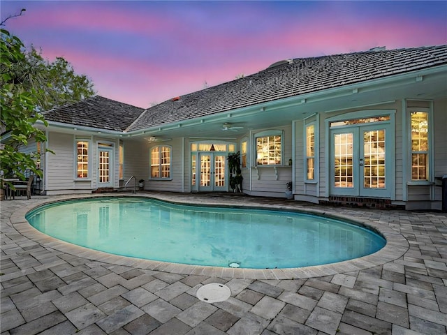 pool at dusk with french doors, a patio area, and an outdoor pool