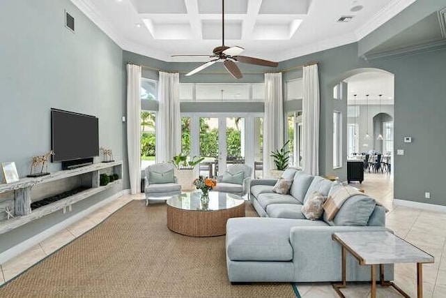 tiled living area featuring arched walkways, coffered ceiling, a towering ceiling, visible vents, and baseboards