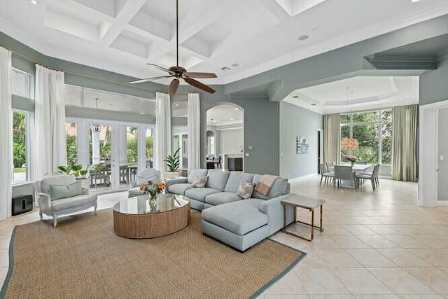 living area featuring arched walkways, light tile patterned flooring, coffered ceiling, ornamental molding, and beam ceiling