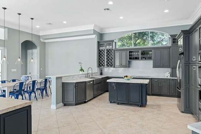 kitchen featuring arched walkways, a sink, ornamental molding, a center island, and tasteful backsplash