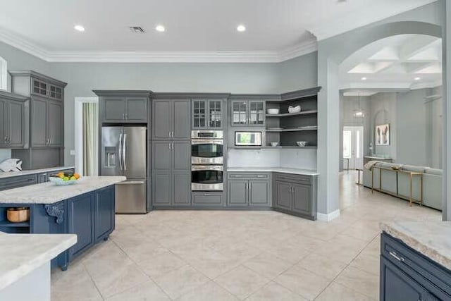 kitchen featuring visible vents, arched walkways, glass insert cabinets, appliances with stainless steel finishes, and crown molding