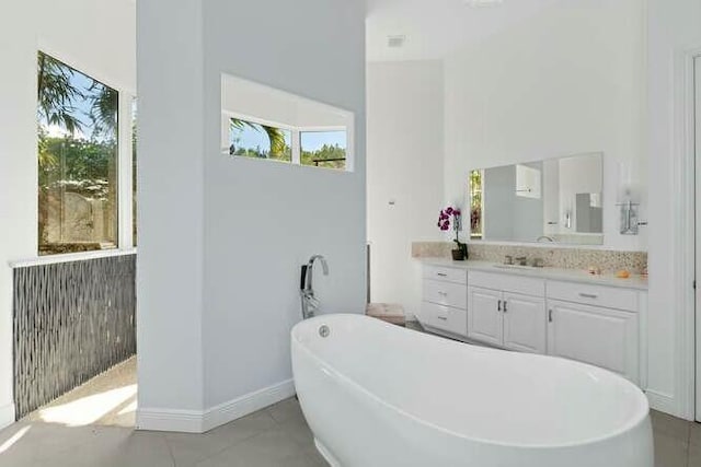 bathroom featuring a freestanding bath, tile patterned flooring, vanity, and baseboards